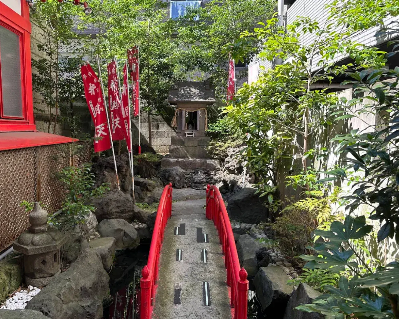 Tsugaru Inari Shrine with red banners tucked between buildings near Kinshicho.