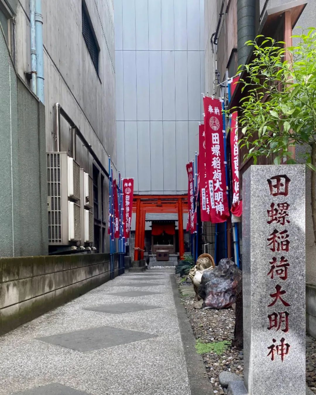 A small shrine detail in Kinshicho with a stone marker, lantern, and offering area.