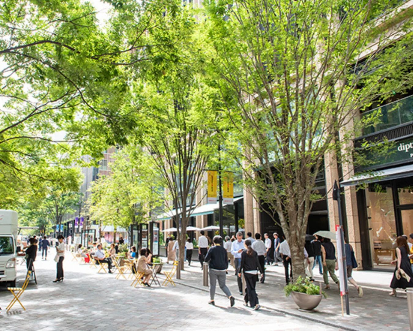 People sitting at outdoor tables on Marunouchi Naka-dori between office towers.