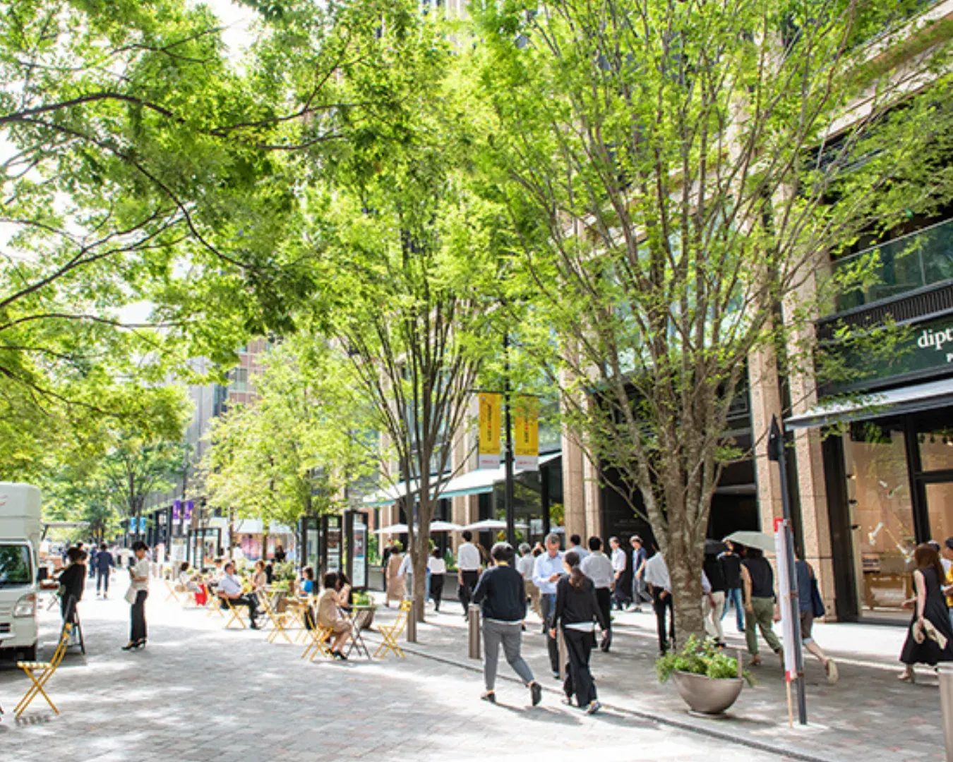 People sitting at outdoor tables on Marunouchi Naka-dori between office towers.