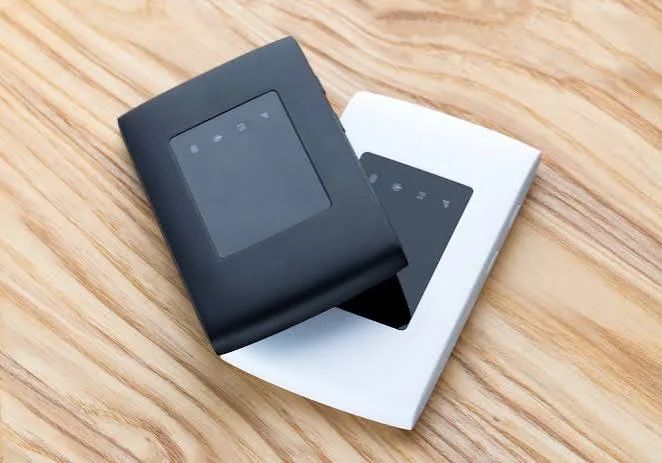 A laptop, phone settings screen, charger, and connection planning note on a Tokyo residence desk.