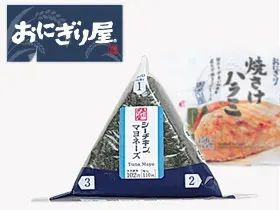 A simple Tokyo convenience store breakfast with onigiri, coffee, and yogurt on a desk.